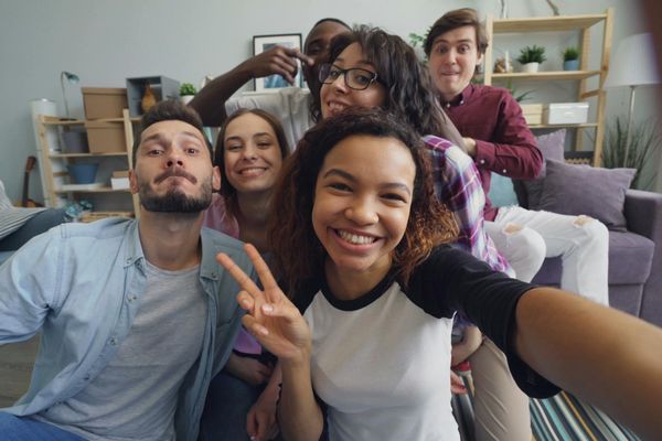 A diverse group of people in comfortable sportswear smiling in a bright room.