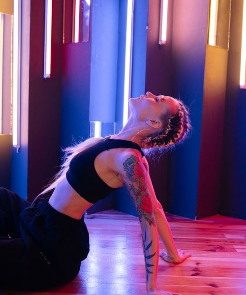 Woman in a dynamic yoga pose with glowing cyan lines accentuating movement.